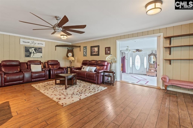 living area featuring wood-type flooring, a ceiling fan, and crown molding