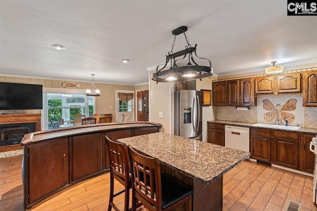 kitchen with stainless steel refrigerator with ice dispenser, a sink, a center island, white dishwasher, and crown molding