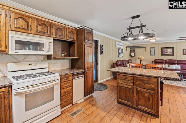 kitchen featuring white appliances, visible vents, crown molding, a kitchen breakfast bar, and open floor plan