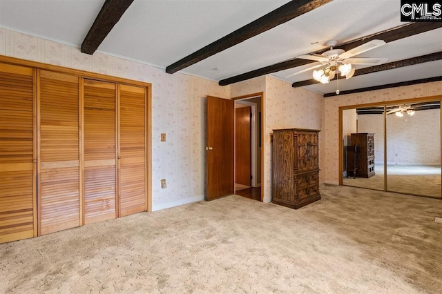 unfurnished bedroom with wallpapered walls, beam ceiling, ceiling fan, a closet, and carpet flooring