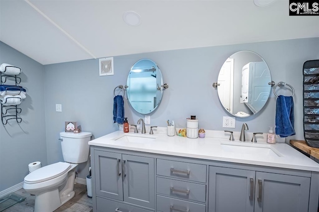 bathroom with double vanity, toilet, baseboards, and a sink