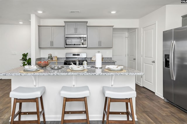 1304 Mosser Dr, Columbia, SC 29203 - kitchen featuring a breakfast bar area, visible vents, dark wood finished floors, gray cabinetry, and stainless steel appliances