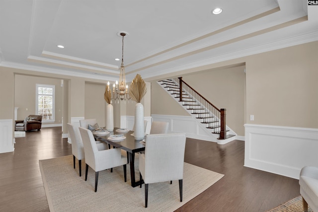 dining area with a tray ceiling, dark wood-type flooring, wainscoting, and stairs