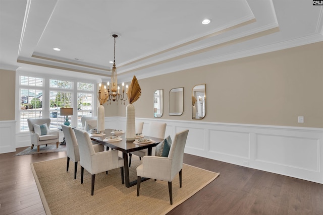 dining room featuring crown molding, wainscoting, a notable chandelier, a raised ceiling, and dark wood-style flooring