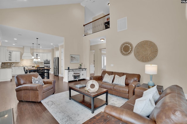 living area featuring visible vents, dark wood finished floors, recessed lighting, an inviting chandelier, and high vaulted ceiling