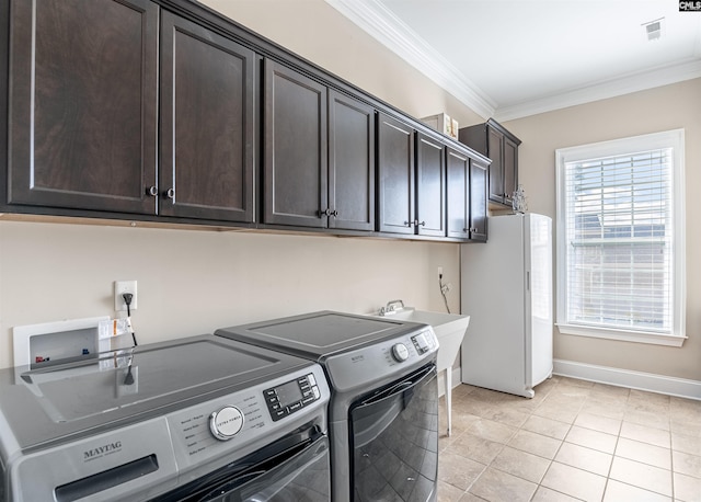 washroom with cabinet space, a healthy amount of sunlight, ornamental molding, and washer and clothes dryer