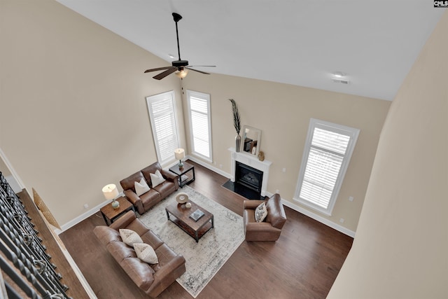 living area with visible vents, baseboards, dark wood finished floors, a fireplace with flush hearth, and lofted ceiling