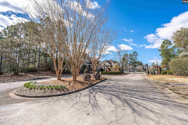 view of road featuring curbs, a residential view, a gated entry, and a gate