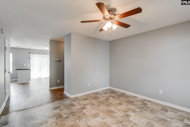 spare room featuring baseboards, a textured ceiling, and a ceiling fan