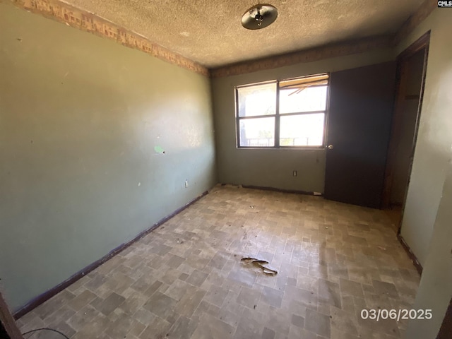 unfurnished room with a textured ceiling