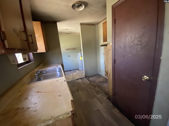 kitchen with a sink, a textured ceiling, water heater, and light countertops