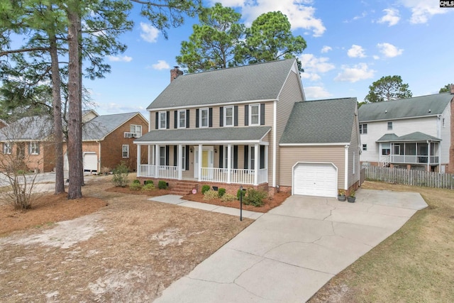 colonial-style house featuring fence, concrete driveway, covered porch, a chimney, and a garage