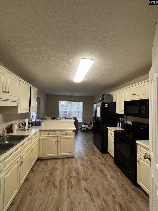 416 Knotts Ct, Lexington, SC 29073 - kitchen with a peninsula, wood finished floors, white cabinets, black appliances, and a sink
