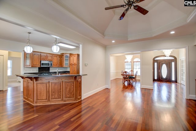 kitchen with brown cabinets, stainless steel microwave, plenty of natural light, dark countertops, and glass insert cabinets