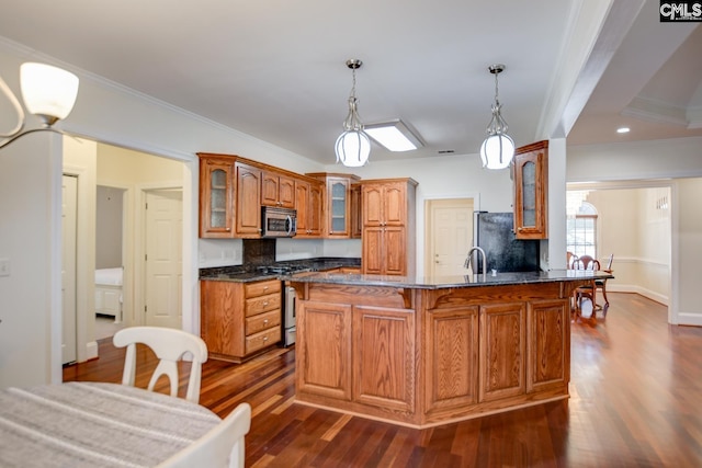 kitchen featuring dark wood finished floors, a peninsula, stainless steel appliances, and glass insert cabinets