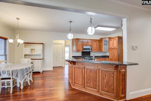 kitchen featuring stainless steel microwave, brown cabinetry, crown molding, glass insert cabinets, and dark wood-style flooring