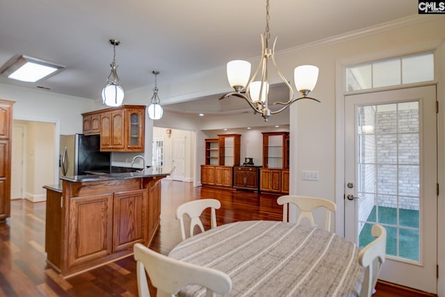 dining area featuring dark wood-type flooring, a chandelier, and crown molding