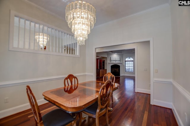 dining room featuring wood finished floors, an inviting chandelier, a fireplace, crown molding, and baseboards