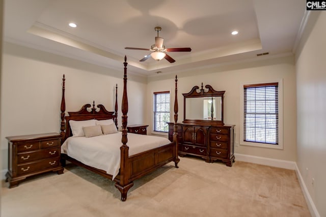 bedroom with visible vents, crown molding, baseboards, light colored carpet, and a tray ceiling