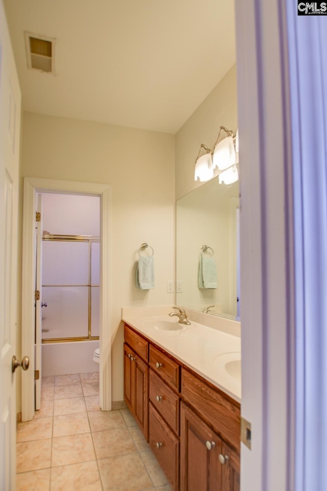 full bathroom featuring visible vents, toilet, double vanity, tile patterned floors, and a sink