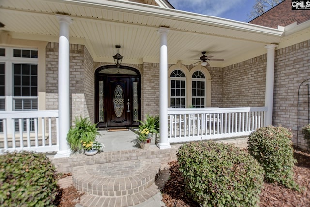 doorway to property with brick siding, covered porch, and ceiling fan