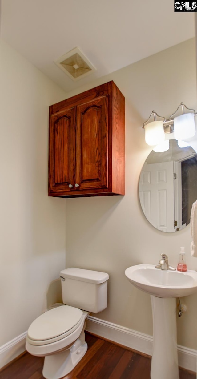 bathroom with visible vents, toilet, baseboards, and wood finished floors