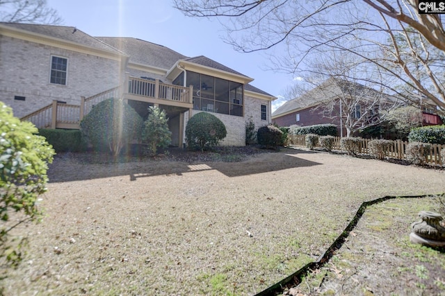 back of house featuring stairway, fence, brick siding, and a sunroom