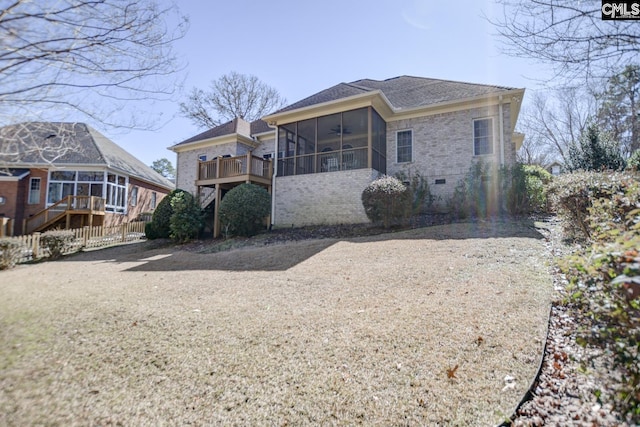 view of front of home with brick siding, crawl space, fence, and a sunroom