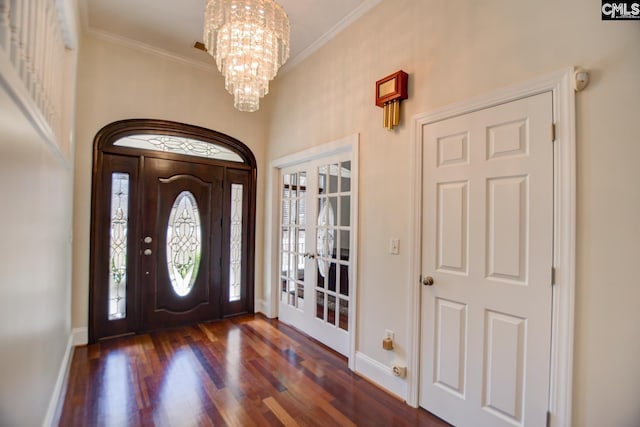 entryway with an inviting chandelier, dark wood-type flooring, crown molding, and baseboards