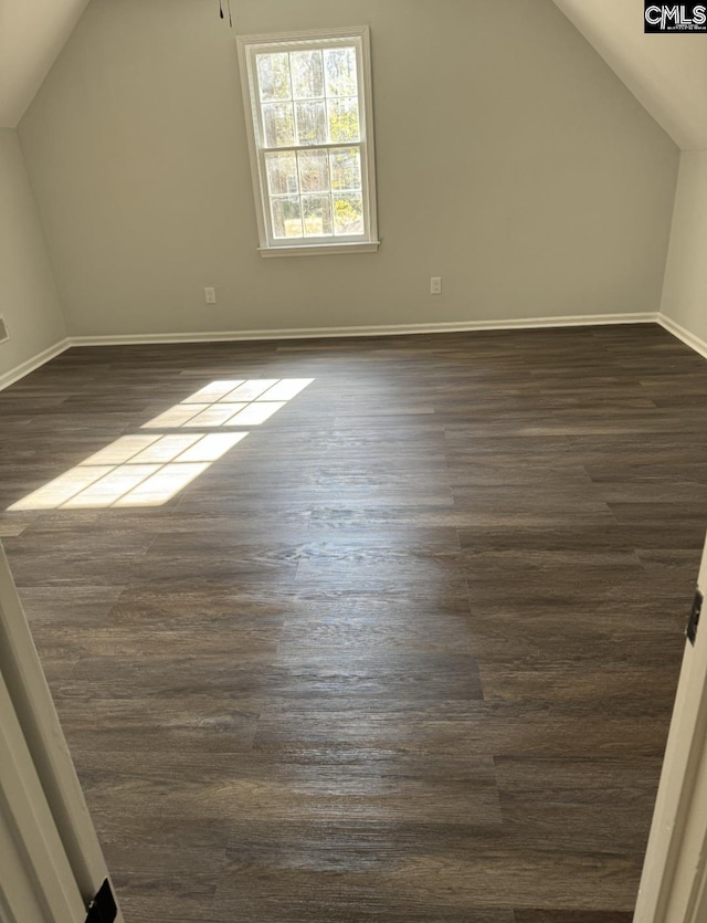 additional living space with vaulted ceiling, baseboards, and dark wood-style flooring