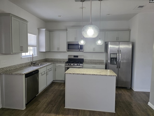 kitchen featuring light stone counters, visible vents, a sink, stainless steel appliances, and a center island