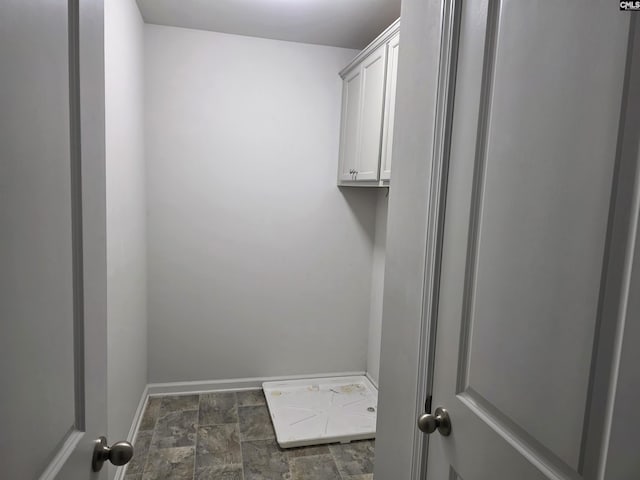 laundry area with baseboards and stone finish flooring