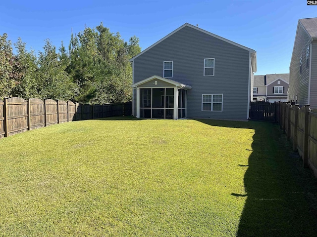 rear view of house with a lawn, a fenced backyard, and a sunroom