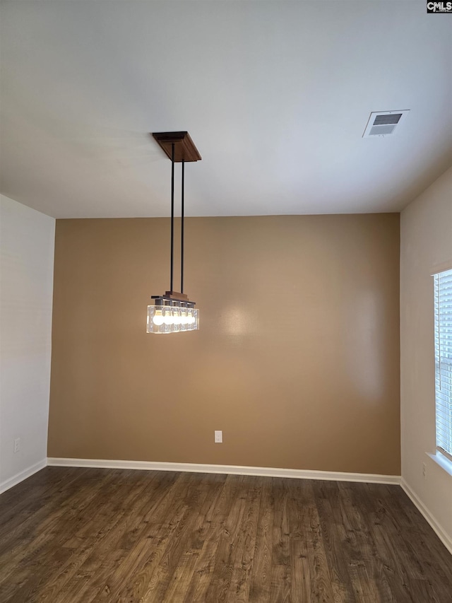 spare room with dark wood-style floors, visible vents, and baseboards