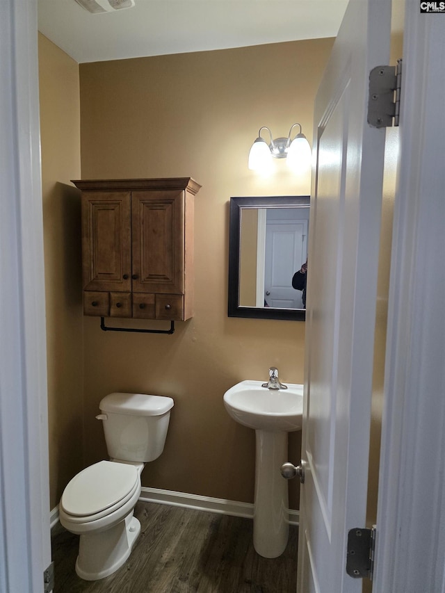 bathroom featuring toilet, wood finished floors, baseboards, and a sink