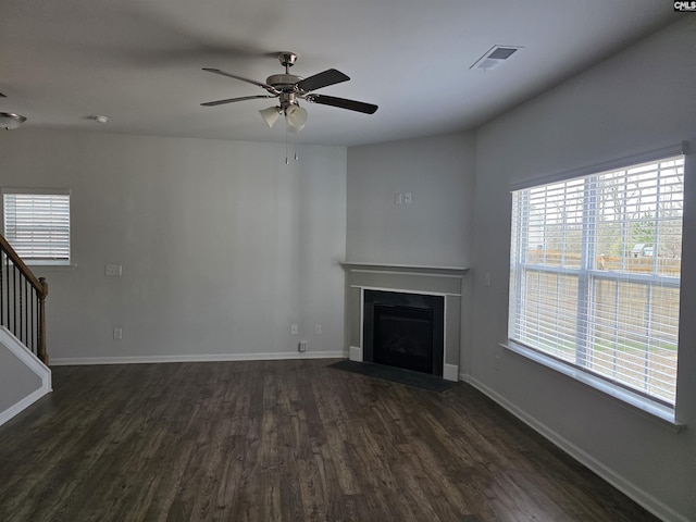 unfurnished living room featuring stairway, a fireplace with flush hearth, a healthy amount of sunlight, and visible vents