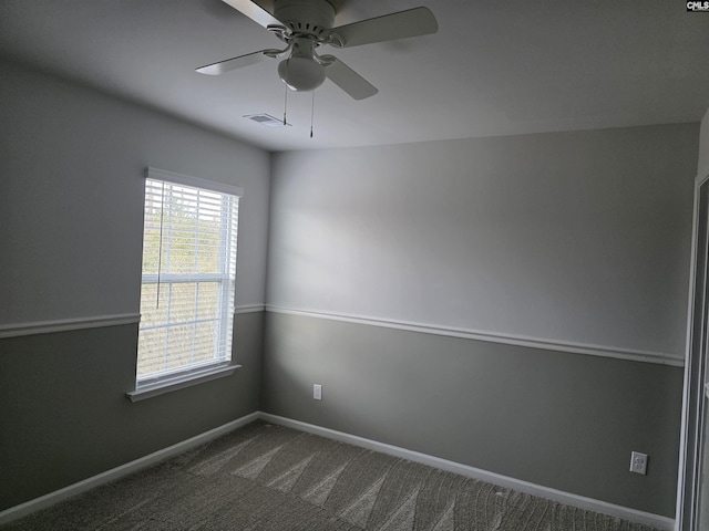 spare room with visible vents, baseboards, a ceiling fan, and dark carpet