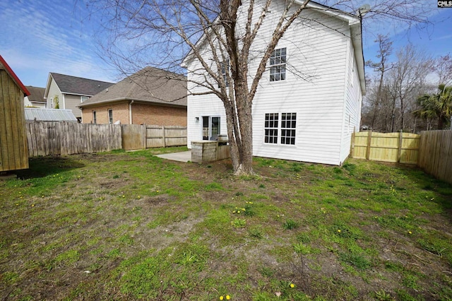 back of house with a patio area, a lawn, and a fenced backyard