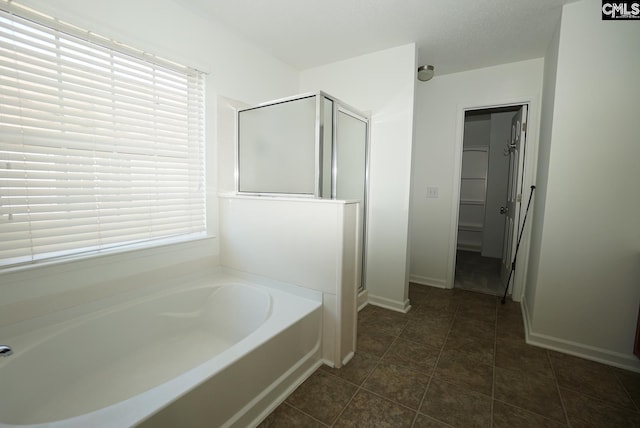 bathroom with tile patterned floors, a bath, baseboards, and a stall shower