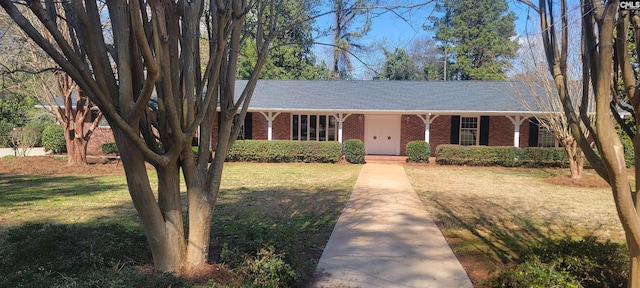 ranch-style home featuring brick siding, covered porch, and a front yard