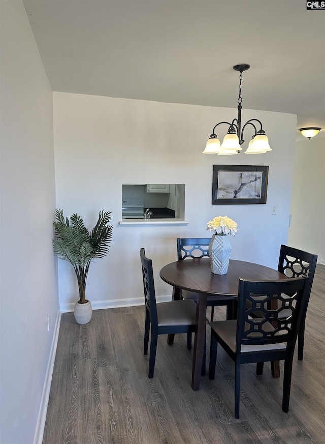 dining space with an inviting chandelier, wood finished floors, and baseboards