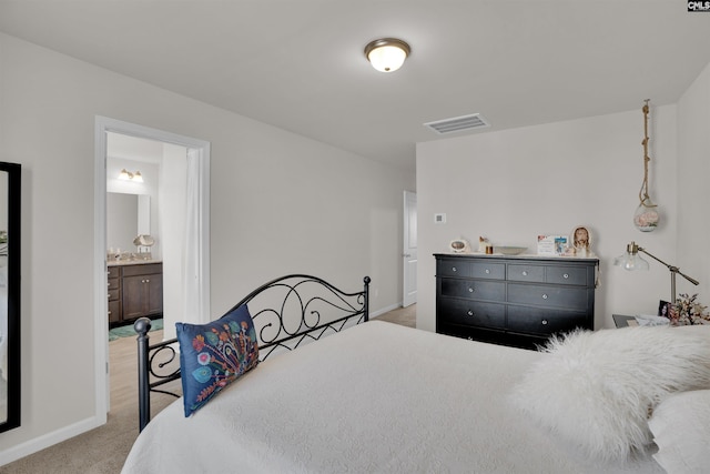 carpeted bedroom with visible vents, baseboards, and connected bathroom