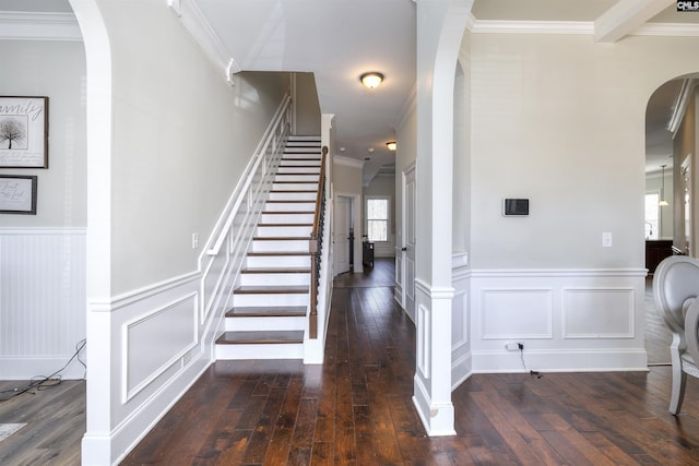 stairs featuring hardwood / wood-style floors, a wainscoted wall, arched walkways, and ornamental molding