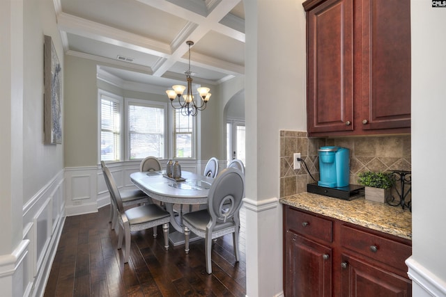 dining area with visible vents, coffered ceiling, dark wood finished floors, an inviting chandelier, and beamed ceiling