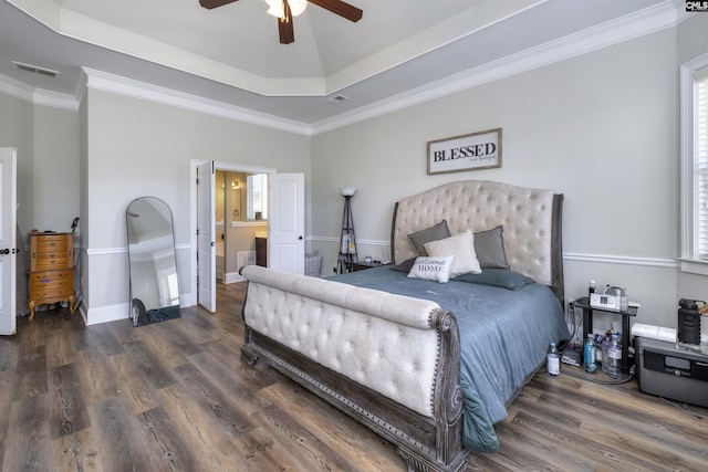 bedroom with a tray ceiling, crown molding, wood finished floors, and baseboards