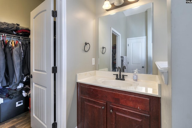 bathroom featuring vanity, wood finished floors, and a spacious closet