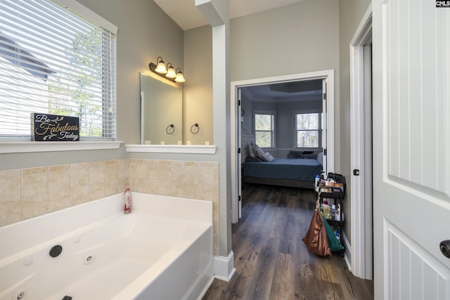 bathroom featuring a jetted tub, wood finished floors, and connected bathroom