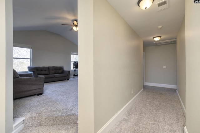 hallway featuring visible vents, baseboards, lofted ceiling, and carpet