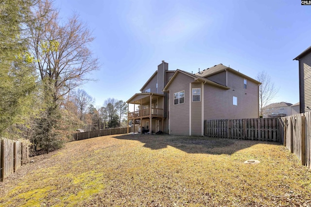 back of property featuring a fenced backyard, a lawn, and a chimney