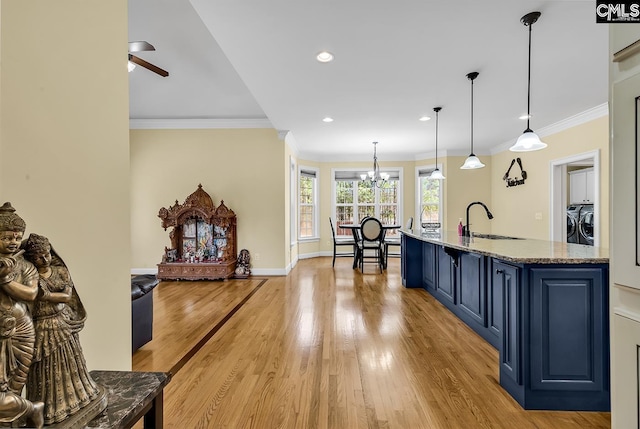 kitchen featuring light wood finished floors, blue cabinetry, ornamental molding, ceiling fan with notable chandelier, and a sink